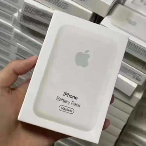 Hand holding the white retail box for the Apple iPhone Battery Pack, which supports MagSafe 15W wireless charging.